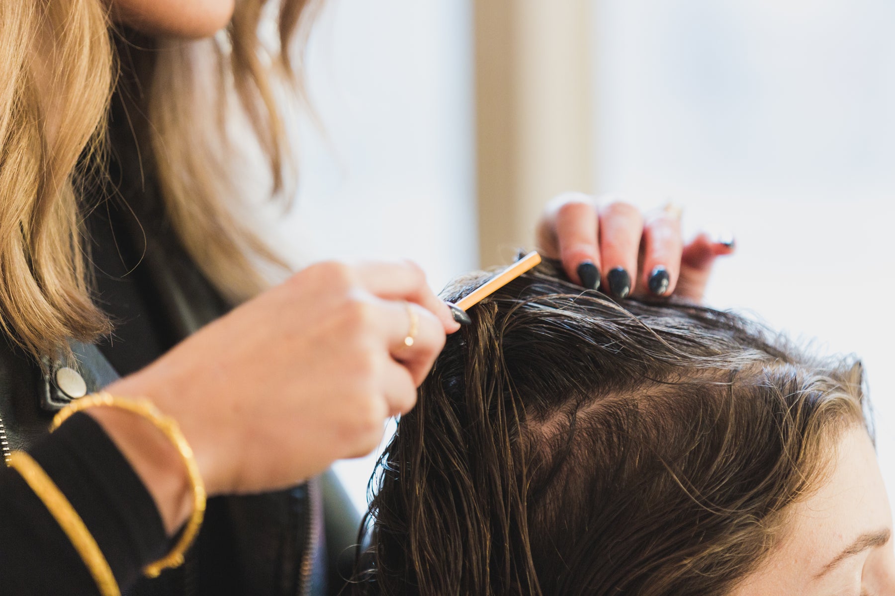Cabeleireira separando mechas na raiz do cabelo