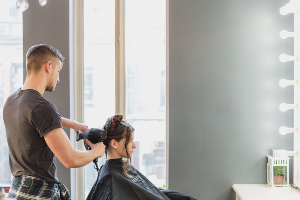 Cabeleireiro finalizando o cabelo da cliente com secador